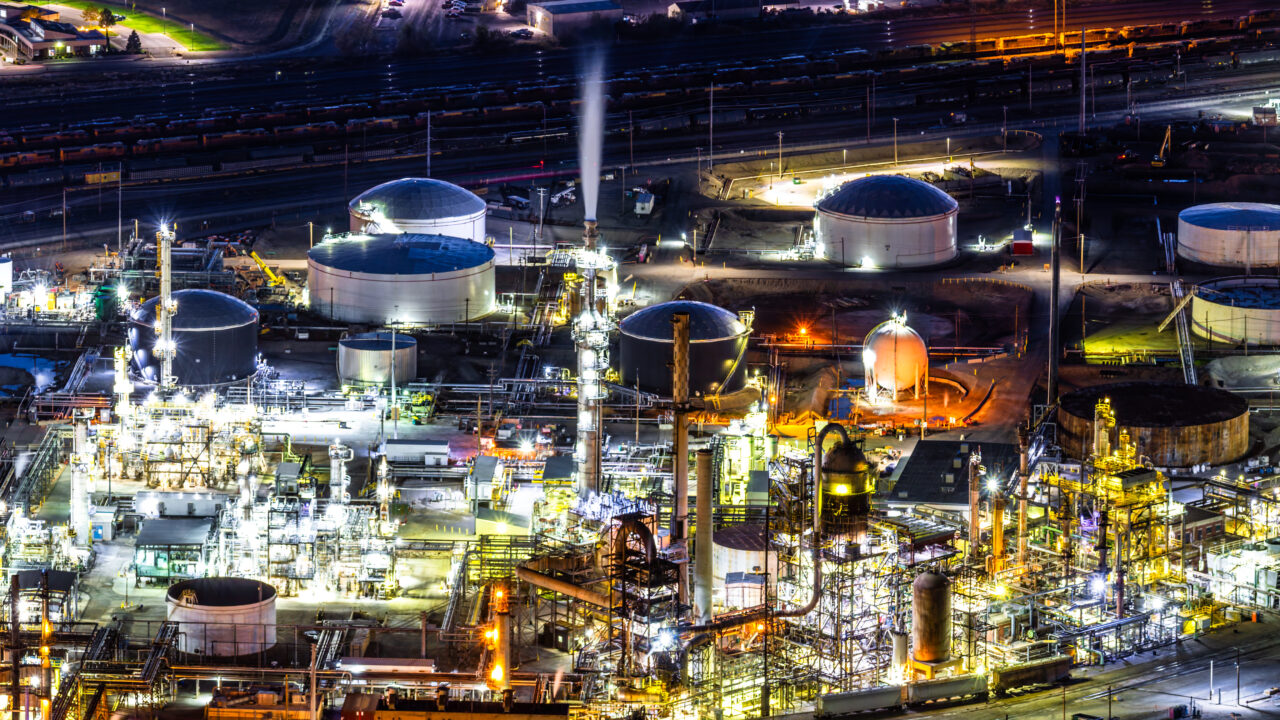 Panoramic view of an illuminated oil refinery plant at night
