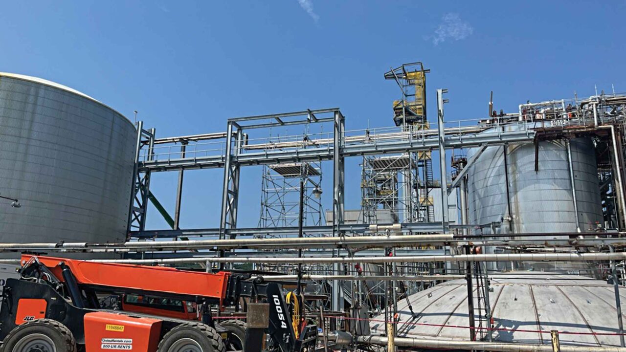 Steel structure and catwalk connecting to existing infrastructure on both sides, with new tank assembly visible in foreground.