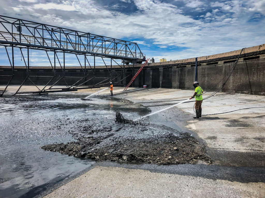 Professionals power washing concrete on an industrial job