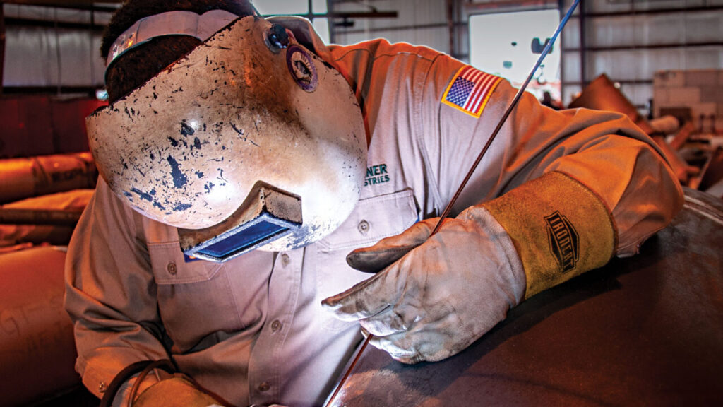 professional in welding gear working on industrial piping